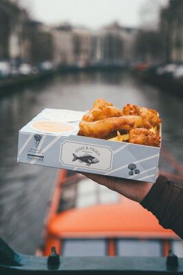 Fish & Fries over an Amsterdam canal with an orange tour boat passing below