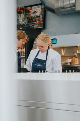 Two staff members working side by side behind the counter, framed by the window